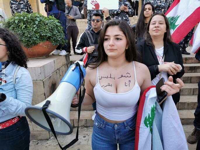 kobieta : Protest w Libanie. Kobieta z napisem na piersiach  "Sama zadecyduję, co na siebie włożę"
