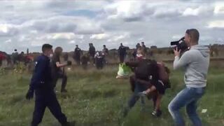 Kamerzystka podstawia nogę biegnącemu imigrantowi z dzieckiem