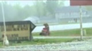 Koleś kosi trawę podczas gradobicia