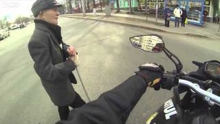 Motocyklista pomaga przejść dziadkowi przez drogę